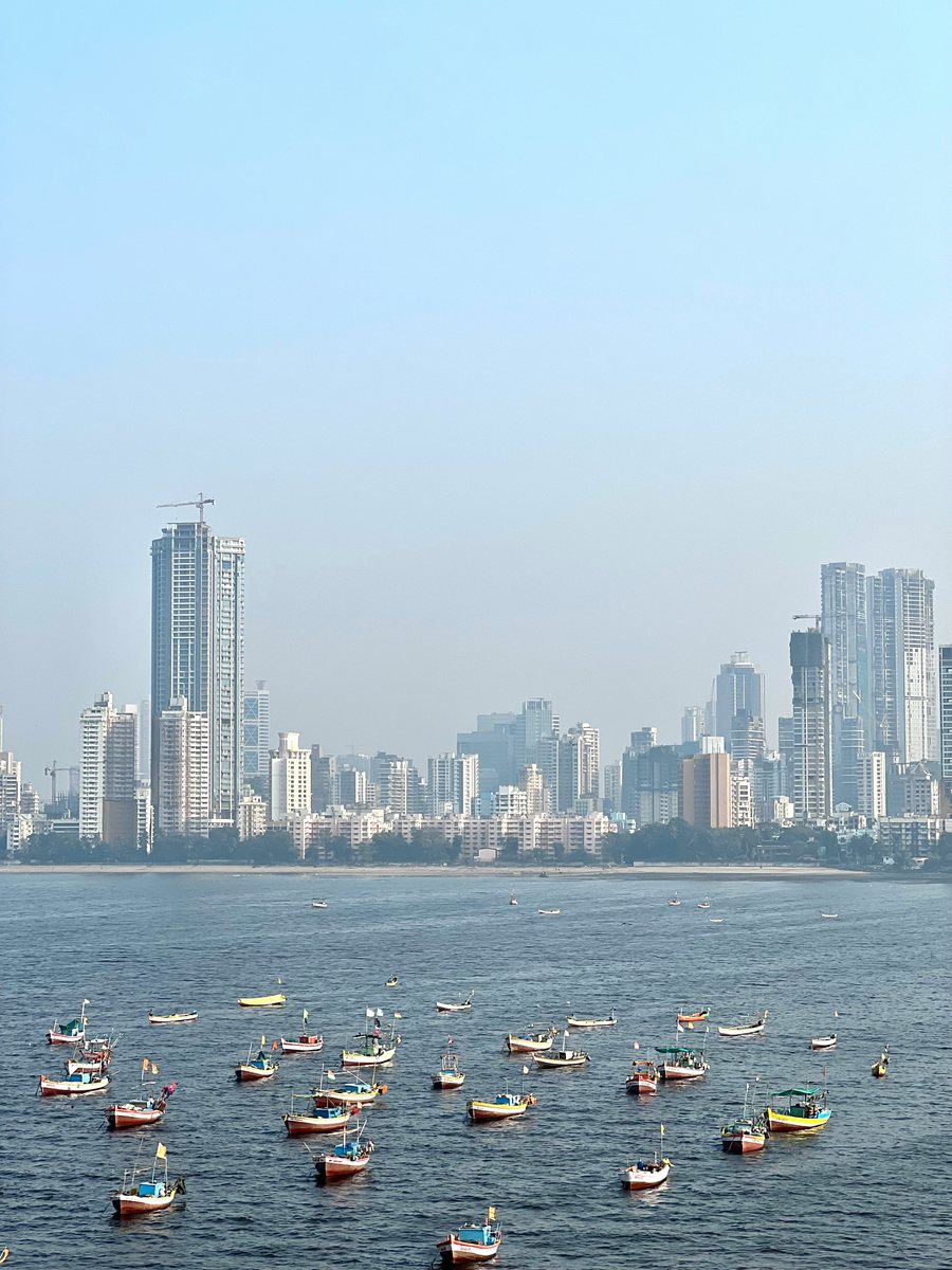 Fishing boats in the foreground with the Mumbai skyline behind